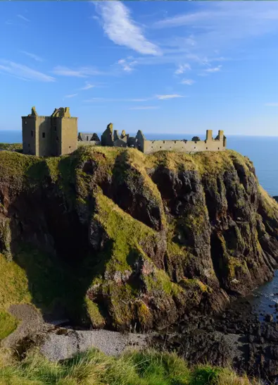 Dunnottar Castle ruins perched dramatically on a sea cliff overlooking the North Sea under a bright blue sky near Stonehaven, Scotland. ?? ''